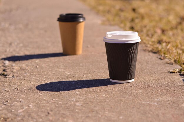 Zdjęcie zbliżenie brązowego kartonu jednorazowego kubka do kawy z czarną plastikową pokrywą rzuca twardy cień