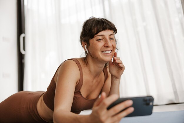 Zbliżenie brunetki sportsmenki robi selfie na telefonie