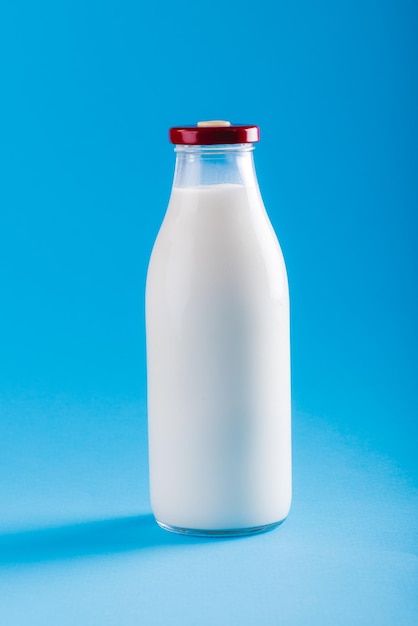 Zdjęcie zbliżenie: butelka mleka na niebieskim tle, przestrzeń. niezmienione, jedzenie, napoje, zdjęcia studyjne i koncepcja zdrowej żywności.