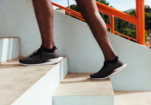 Zbliżenie butów atlety nóg młody biegacz sportowy czarny mężczyzna podbiega do wchodzenia po schodach, wykonując trening cardio sport na ulicy na świeżym powietrzu, zdrowe ćwiczenia przed koncepcją treningu