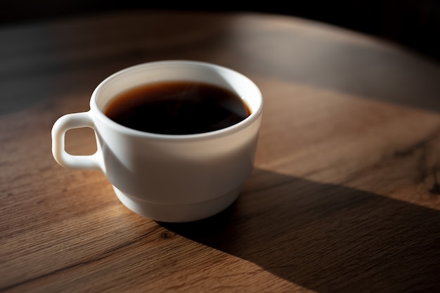 Zbliżenie ceramiczna filiżanka kawy na drewnianym stole.