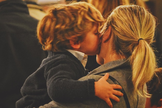Zdjęcie zbliżenie chłopca całującego matkę