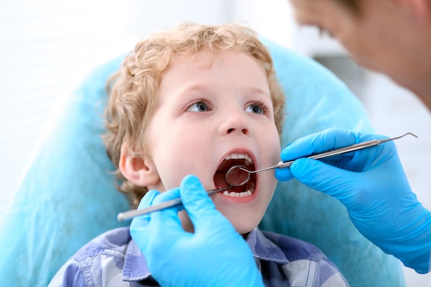 Zbliżenie chłopca o zęby zbadane przez dentystę.
