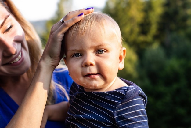 Zdjęcie zbliżenie chłopczyk z mamą uśmiecha się i przytula razem na zewnątrz rodzina powolna podróż z dziećmi