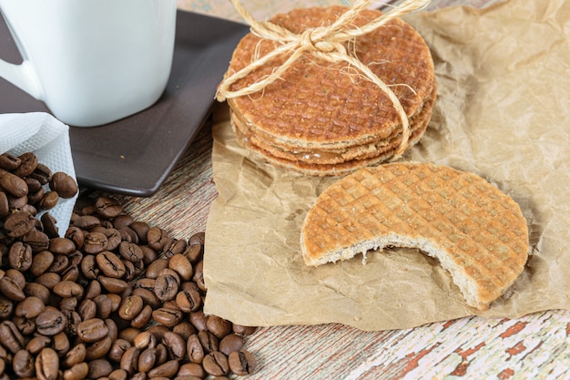 Zbliżenie Ciasteczka Stroopwafel Z Ugryzieniem Obok Fasoli I Filiżankę Kawy.