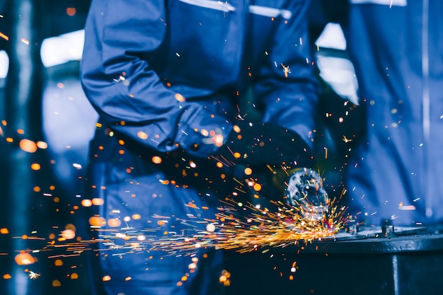 Zbliżenie ciężki stalowy pracownik używa elektrycznego koła szlifierskiego dyska tnącego metalu talerza w miejscu pracy