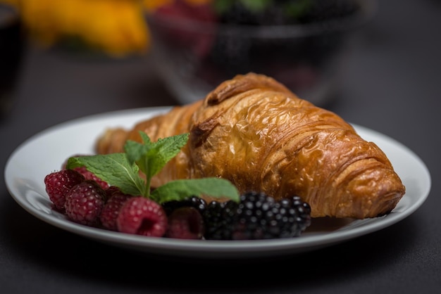 Zbliżenie croissant z jagodami na talerzu na stole