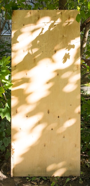 Zbliżenie czarnego cienia liści od światła słonecznego na brązowej powierzchni sklejki