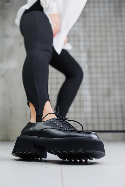 Zdjęcie zbliżenie czarnych skórzanych sznurowanych butów na kobiecych nogach w czarnych legginsach stylowe jesienne buty damskie