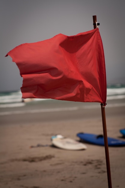 Zdjęcie zbliżenie czerwonej flagi na plaży na tle nieba