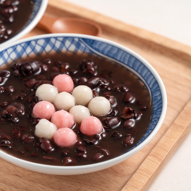 Zbliżenie Czerwony I Biały Tangyuan (tang Yuan, Kleisty Ryż Kluski Kulki) Ze Słodką Zupą Z Czerwonej Fasoli W Misce Na Białym Tle Tabeli Na Festiwal Przesilenia Zimowego.