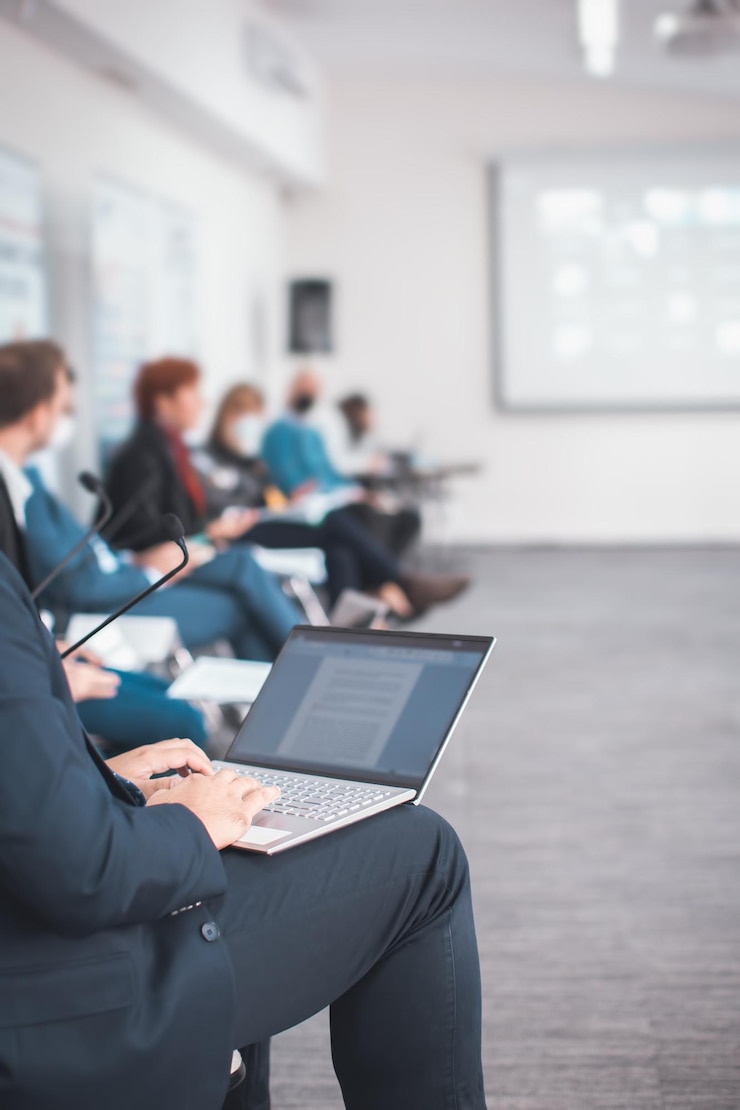 Zdjęcie zbliżenie człowieka korzystającego z laptopa robiącego notatki podczas prezentacji seminarium