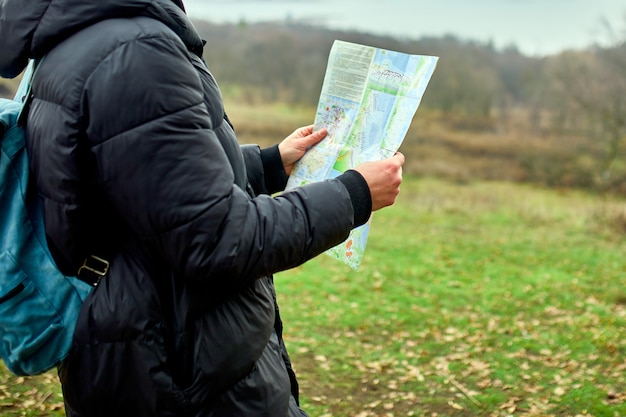 Zbliżenie Człowieka Podróżnika Z Plecakiem Z Mapą W Ręku Na ścianie Gór Rzeki Natury, Koncepcja Podróży, Wakacje I Koncepcja Pieszych Wędrówek Stylu życia