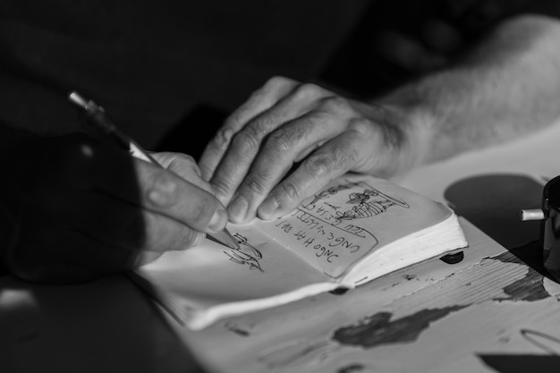 Zdjęcie zbliżenie człowieka rysującego w książce na stole