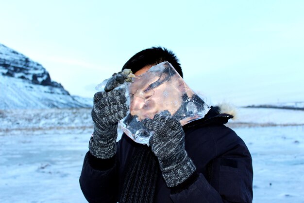 Zbliżenie człowieka trzymającego lód na tle nieba