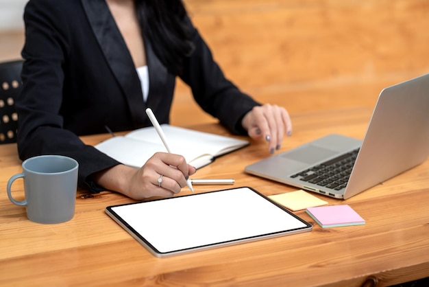 Zbliżenie dłoni bizneswoman trzymającej rysik pracujący za pomocą tabletu laptopa notebook umieszczonego w biurze.