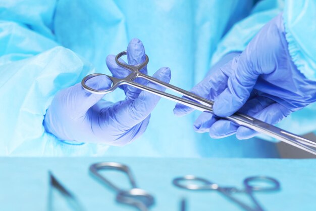Zbliżenie dłoni chirurgów w pracy na sali operacyjnej w odcieniach niebieskiego