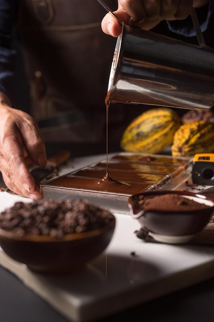 Zbliżenie dłoni czekoladnika wlewającego czekoladę do foremek
