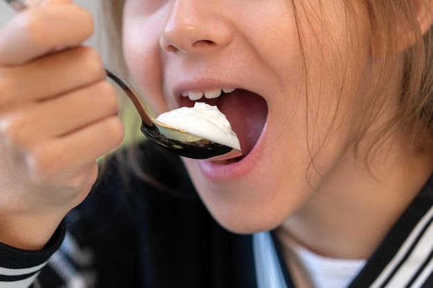 zbliżenie dłoni dziewczyny jedzącej waniliowy biały jogurt z plastikowego pudełka Dziecko jedzące smaczny jogurt w domu