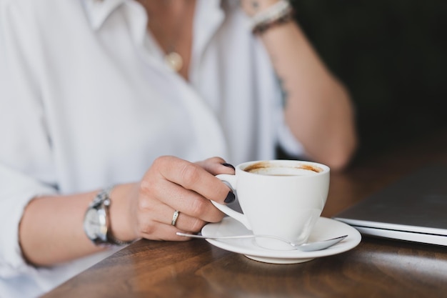 Zbliżenie dłoni kobiet przy filiżance kawy przy stole w kawiarni