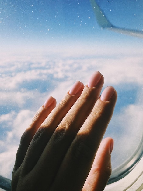 Zdjęcie zbliżenie dłoni kobiety na oknie samolotu