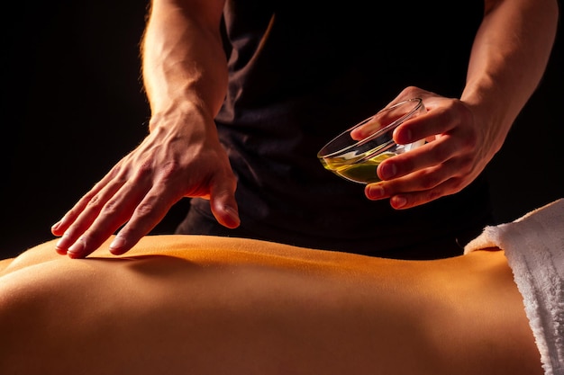 Zbliżenie dłoni masażysty robi masaż pleców klientce w centrum spa panchakarma.