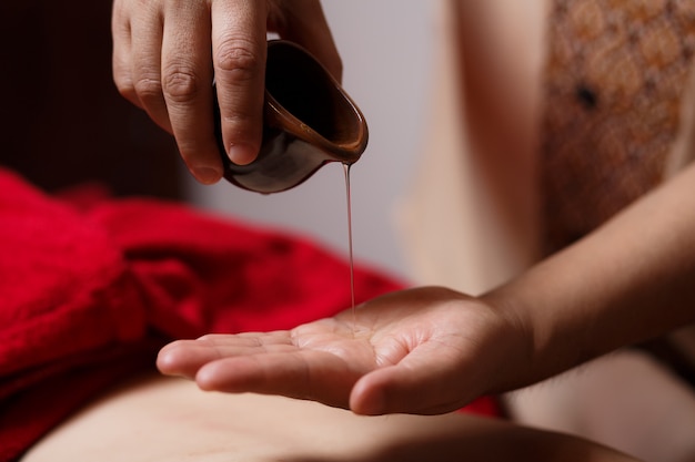 Zbliżenie dłoni masażysty spływa po jego dłoni kropla olejku do masażu