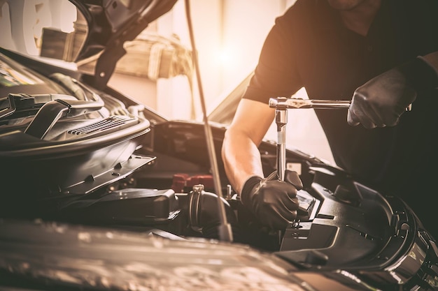 Zbliżenie dłoni mechanika samochodowego za pomocą klucza do naprawy problemu z silnikiem samochodu Koncepcje sprawdzania i naprawy samochodu oraz serwisowania