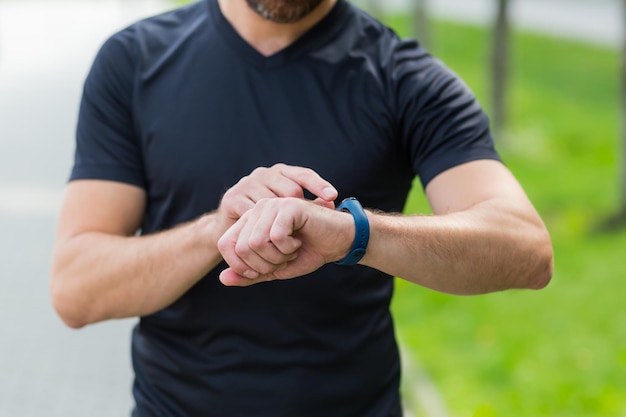 Zbliżenie dłoni męskiego sportowca przełączającego program fitness w inteligentnym zegarku