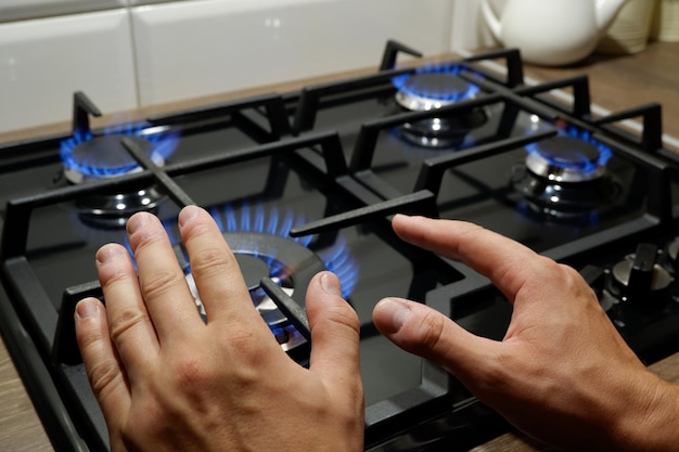 Zbliżenie dłoni mężczyzny w pobliżu kuchenki gazowej Mężczyzna grzeje ręce przy kuchence z powodu słabego ogrzewania w domu Sezon włączenia ciepła na Ukrainie Rosja