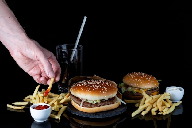 Zbliżenie Dłoni Mężczyzny Zanurzającej Frytki W Keczup świeży Smaczny Hamburger Na Czarnym Tle