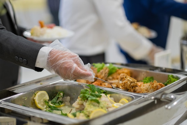 Zbliżenie dłoni noszącej rękawiczki nabierające jedzenie catering czas obiadowy zapobiega chorobie koronawirusowej covid 19xAxA