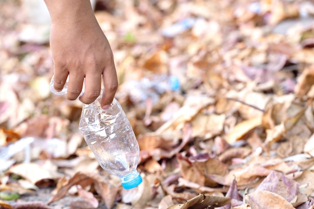 Zbliżenie dłoni podnieś plastikową butelkę z wodą. oszczędzaj środowisko i walcz z zanieczyszczeniami z tworzyw sztucznych.