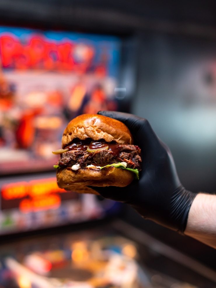 Zdjęcie zbliżenie dłoni trzymając smaczny grillowany burger wołowy z sałatą i majonezem.
