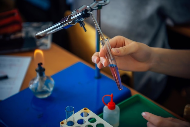 Zbliżenie dłoni ucznia trzymającej roztwór chemiczny do kolby. Dziecko w wieku szkolnym przeprowadza eksperymenty chemiczne w klasie. Koncepcja edukacji przyrodniczej dzieci.