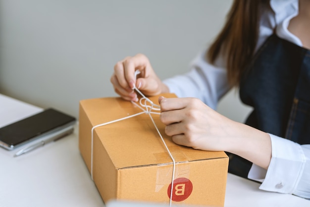 Zbliżenie dłoni właściciela małej firmy online pakującej paczkę dla klienta.
