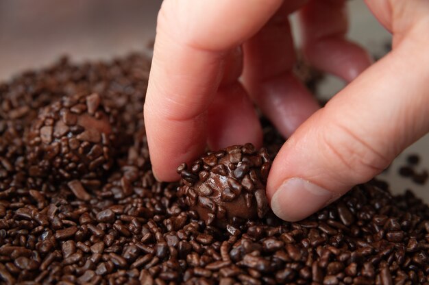 Zbliżenie Dłoni Zbierającej Pyszne I Tradycyjne Brazylijskie Cukierki O Nazwie Brigadeiro W Brazylijskim Portugalskim