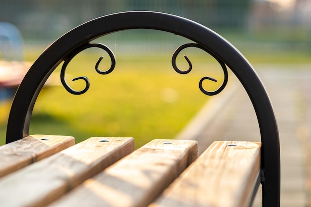 Zbliżenie drewnianej ławce w parku z metalowym uchwytem na zewnątrz.