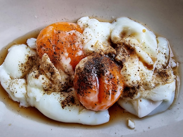 Zbliżenie dwa jajka na miękko z sosem sojowym i pieprzem w misce
