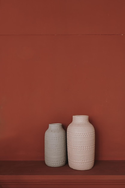 Zbliżenie dwóch ceramicznych wazonów na głębokim czerwonym tle