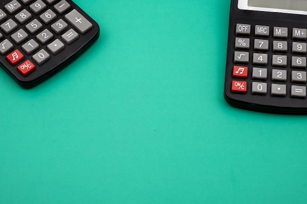 Zbliżenie dwóch kalkulatorów na zielonym stole.