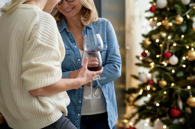 Zdjęcie zbliżenie dwóch kobiet stojących z kieliszkami wina