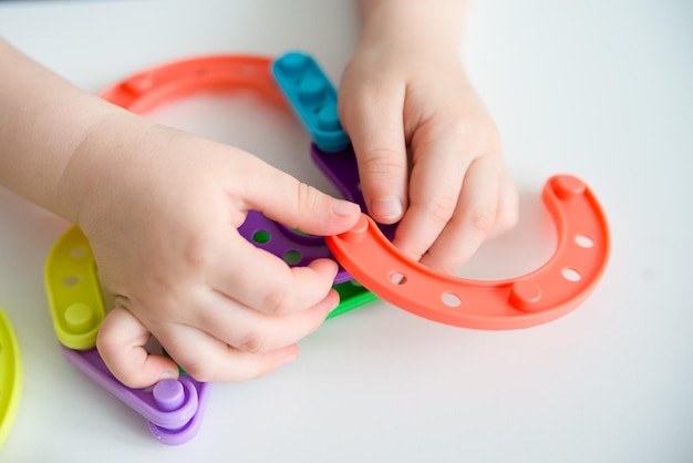 Zdjęcie zbliżenie dziecięcych rąk bawiących się jasnymi plastikowymi zabawkami konstruktor kreatywny dziecko tworzy nowe formy kopiować przestrzeń