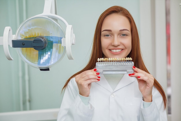 Zbliżenie dziewczyna z pięknym uśmiechem przy dentystą. Dentystyczny. Dentysta pasujący do koloru zębów w biurze.