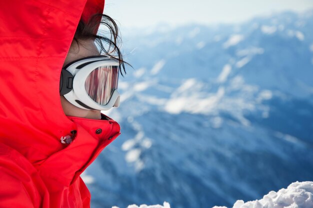 Zdjęcie zbliżenie dziewczyny na nartach z goglami na tle gór
