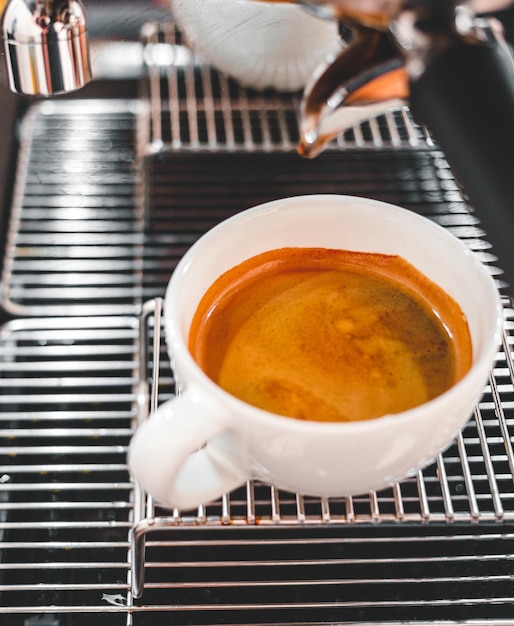 Zbliżenie ekstrakcji kawy z ekspresu do kawy z portafiltrem nalewającym kawę do filiżanki