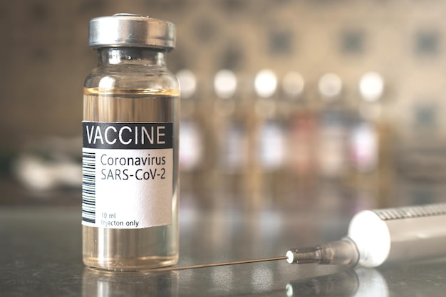 Zbliżenie etykiety fiolki szczepionki koronawirusa COVID-19 ze strzykawką, wykształceniem medycznym, opracowaniem szczepionki i zdjęciem koncepcji procesu produkcji