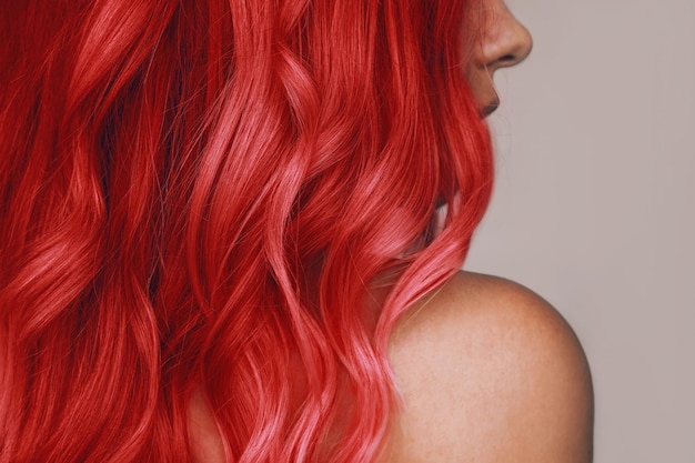 Zbliżenie falistych gorących rudych włosów młodej kobiety odizolowanej na beżowym tle Wynik kolorowania