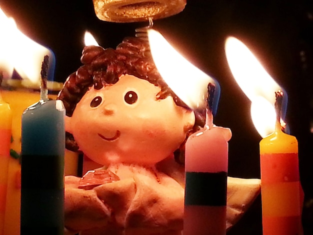 Zdjęcie zbliżenie figurki kobiety przy oświetlonych świecach urodzinowych