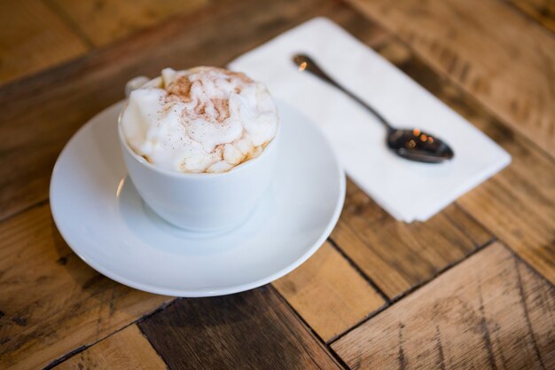 Zbliżenie: filiżanka kawy podana na drewnianym stole w kawiarni